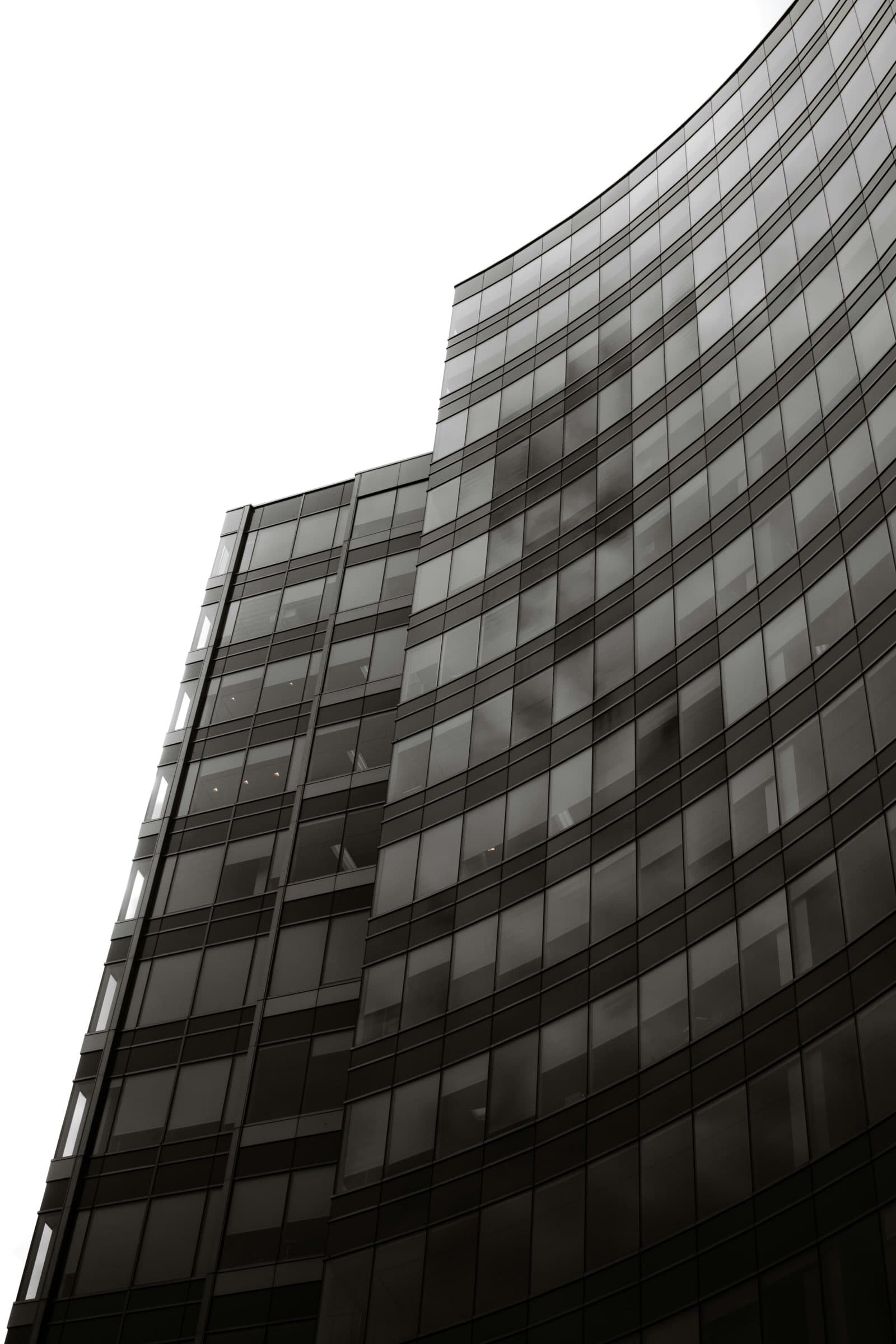 A modern glass office tower rising into a clear sky.