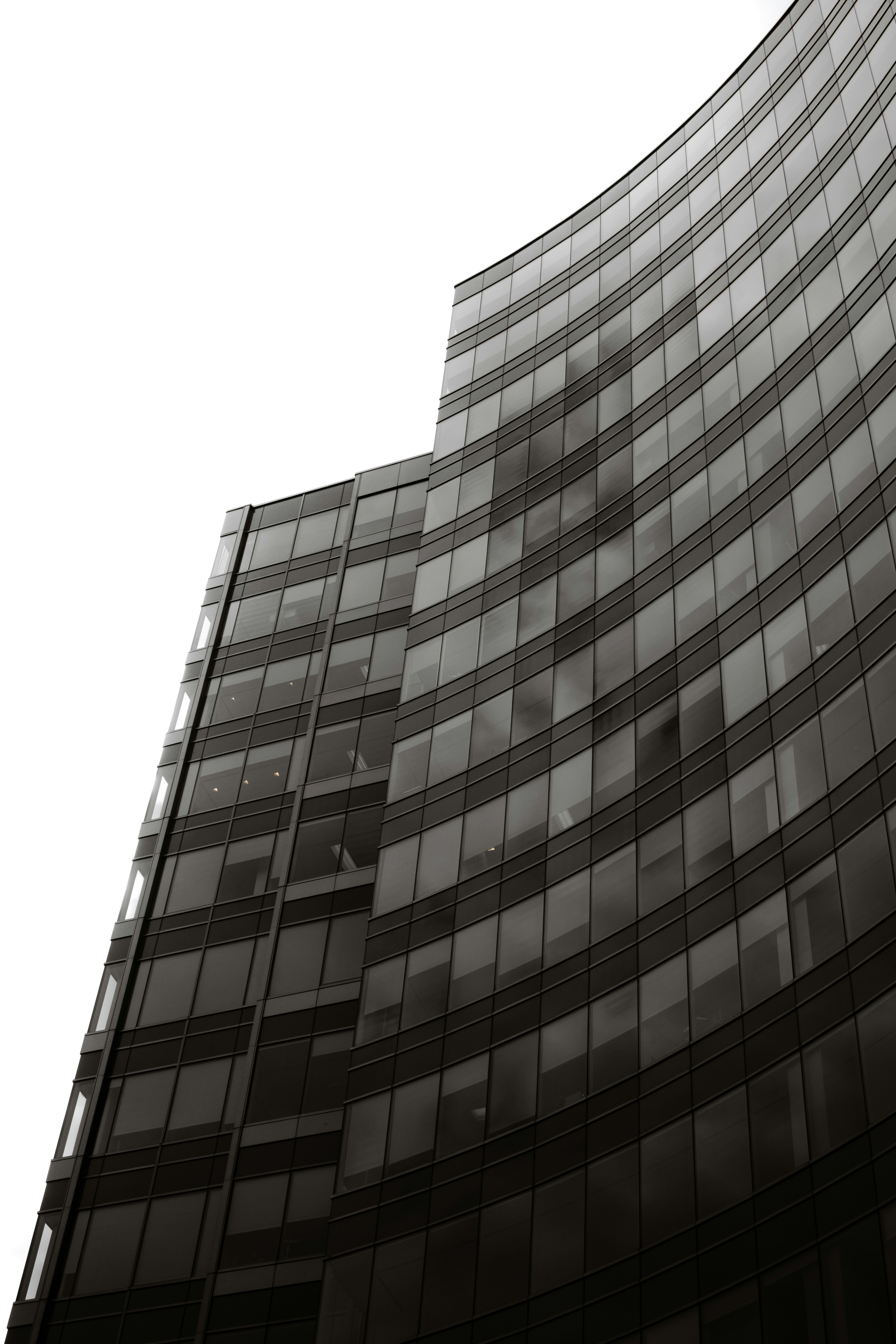 A modern glass office tower rising into a clear sky.